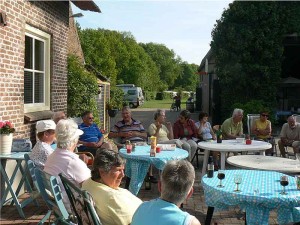 Mensen zitten aan tafeltjes met wijn op de kleine camping Gelderland