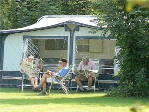 Mensen lezen de krant voor de caravan op de kleine camping Gelderland