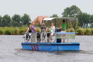 Mensen met fietsen op de pont bij de kleine camping Friesland
