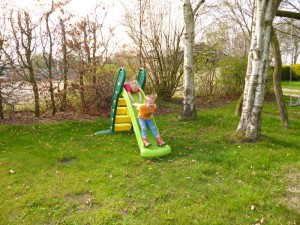 Kinderen glijden van de plastic glijbaan op de boerencamping Gelderland