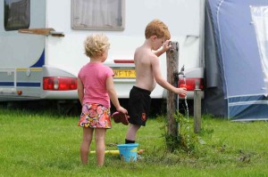 Twee kinderen bij een kraantje op de kleine camping Friesland