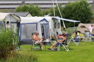 Mensen aan tafel voor de tent op de kleine camping Friesland