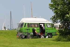 Een groene campervan op de kleine camping Friesland