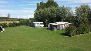 Een caravan en een tent op de kleine camping Zeeland