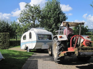 Een tractor trekt een caravan op de kleine camping Limburg