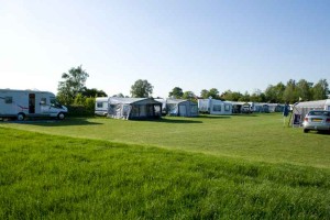 Het groene grasveld met kampeerders op de boerencamping Gelderland
