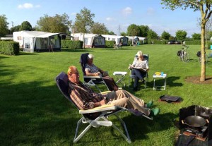 Drie mensen luieren in campingstoelen op de kleine camping Limburg