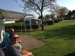 Twee mensen zitten in de zon bij de caravan op de kleine camping Limburg