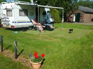 Een witte camper met mensen in stoeltjes op de kleine camping Overijssel