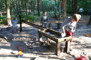 Kinderen spelen met een waterbaan op een kleine camping in Gelderland