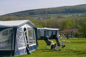 Een man in de zon voor de tent op de boerencamping Limburg