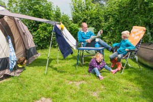 Een vader met twee kinderen voor de tent op de boerencamping Utrecht