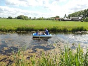 Een man en een meisje in een kleine roeiboot in de sloot op de boerencamping Utrecht