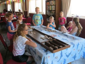 Kinderen sjoelen binnen op de boerencamping Gelderland