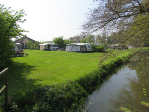 Een groen grasveld met een sloot op de boerencamping gelderland