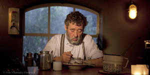 Een man aan tafel in klassieke kledij op de boerencamping Brabant