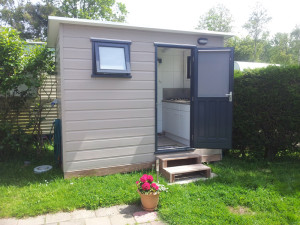 Een grijze chalet op de boerencamping aan zee