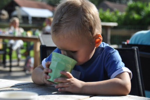 Een klein jongetje drinkt uit een groene beker op de kleine camping Brabant