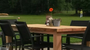Een houten eettafel met een oranje bloem op de kleine camping Brabant