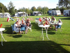 Mensen eten buiten in de zon een van de kleine campings Gelderland