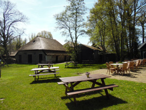 Picknicktafels en rieten stoelen voor een boeren huis met een rieten dak