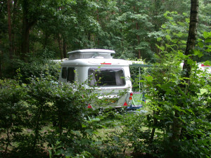 Een witte caravan in het bos van een boerencamping brabant