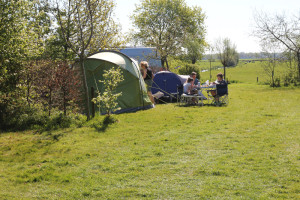 Mensen eten aan tafel voor hun tent op het kampeerterrein van natuurcamping drenthe