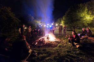 Een kampvuur met mensen in de nacht op de kleine camping