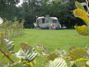 Een witte caravan op een groen grasveld op een natuurcamping zuid holland