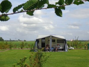 Een caravan op het groene grasveld op natuurcamping zuid holland