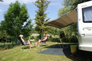 MEsen in de zon naast hun caravan op een kleine campings frankrijk
