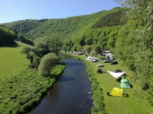 Een rivier loopt door het groene landschap bij de boerencamping