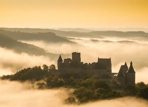 Een mistig landschap met een kasteel bij de boerencamping