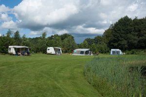 Grasveld met caravans en tenten. Boek met de camping card
